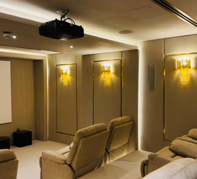 Luxury home theatre system in Dubai featuring comfortable recliners, wall-mounted acoustic panels, and ambient lighting.
