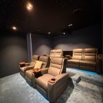Luxury home cinema showing the ideal home cinema room size with projector screen, reclining seats, KEF speakers, acoustic wall panels, and fiber optic lighting in a Dubai villa.