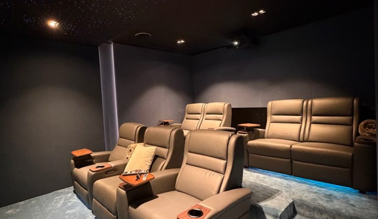 Luxury home cinema showing the ideal home cinema room size with projector screen, reclining seats, KEF speakers, acoustic wall panels, and fiber optic lighting in a Dubai villa.