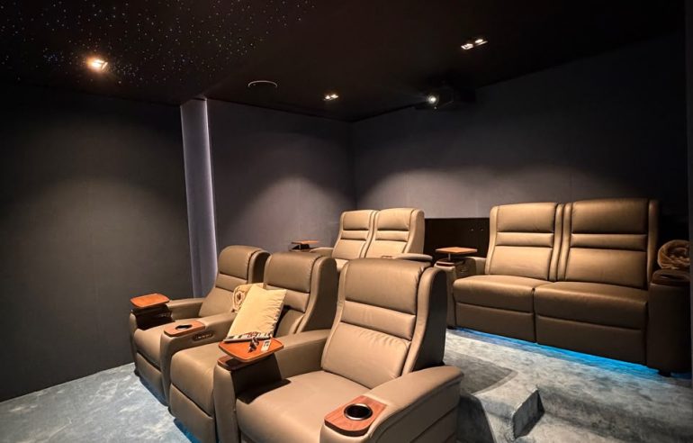 Home Cinema Room Size Guide: How Much Space Do You Really Need? 1 Luxury home cinema showing the ideal home cinema room size with projector screen, reclining seats, KEF speakers, acoustic wall panels, and fiber optic lighting in a Dubai villa.