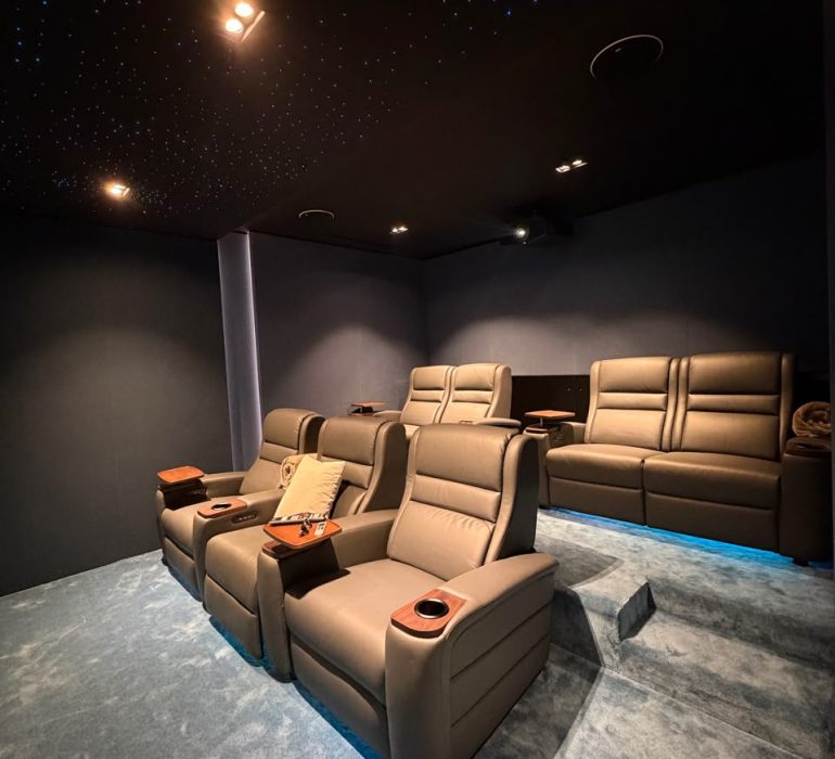 Home Cinema Room Size Guide: How Much Space Do You Really Need? 11 Luxury home cinema showing the ideal home cinema room size with projector screen, reclining seats, KEF speakers, acoustic wall panels, and fiber optic lighting in a Dubai villa.
