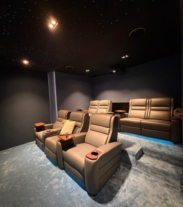 Luxury home cinema showing the ideal home cinema room size with projector screen, reclining seats, KEF speakers, acoustic wall panels, and fiber optic lighting in a Dubai villa.